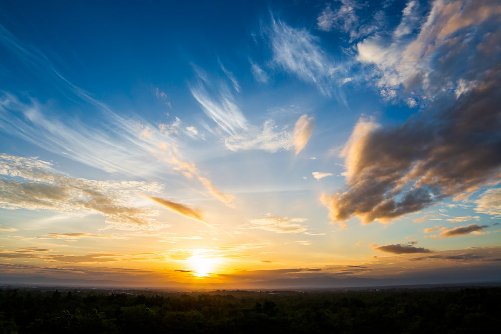 colorful-dramatic-sky-with-cloud-at-sunset-2025-02-11-09-28-40-utc.jpg Sunset over a landscape with a mix of clouds in the sky and a faint silhouette of the horizon below.
